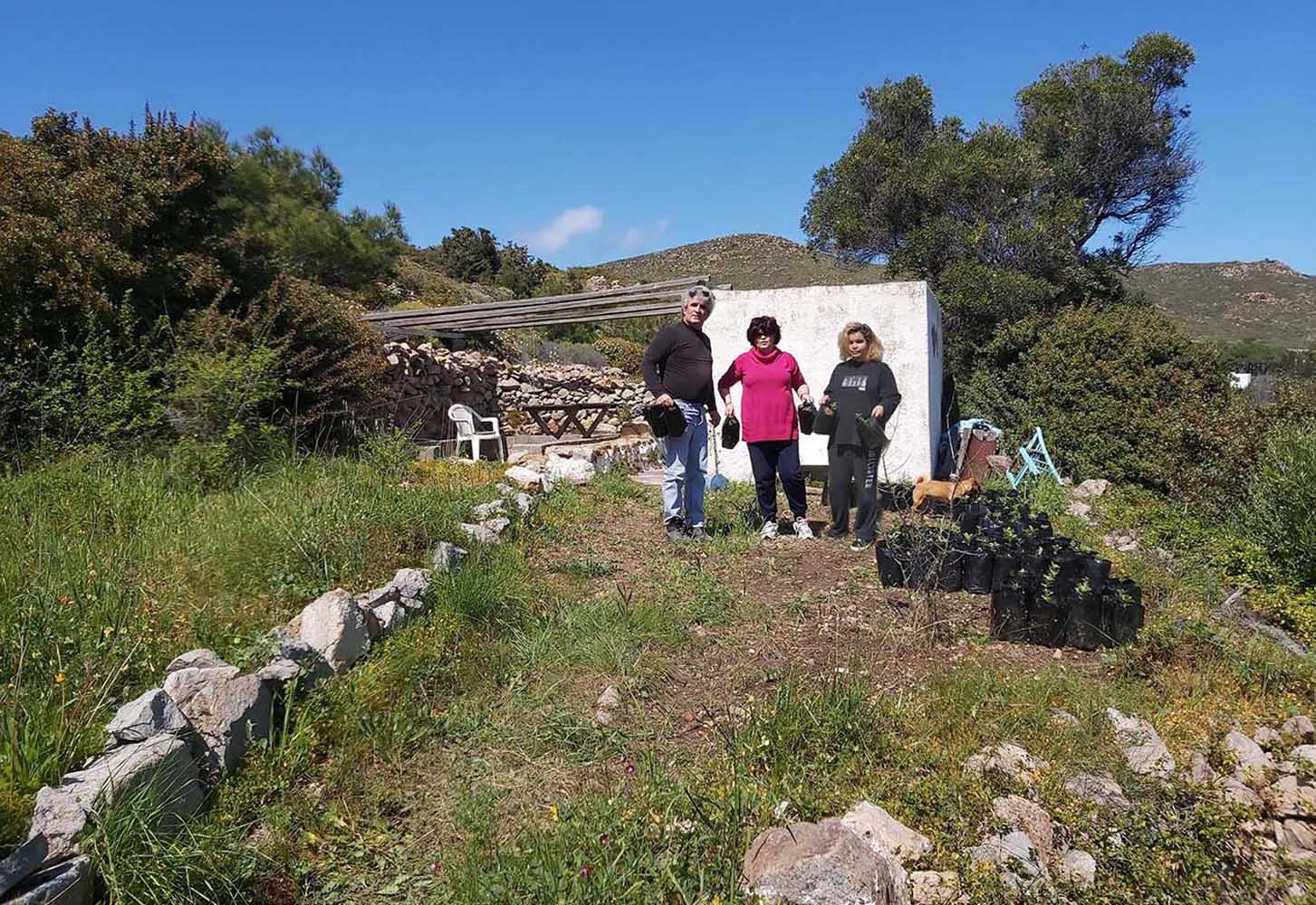 Τρεις άνθρωποι δίπλα σε φυτώριο με μικρά δέντρα στον λόφο του Κουμά.