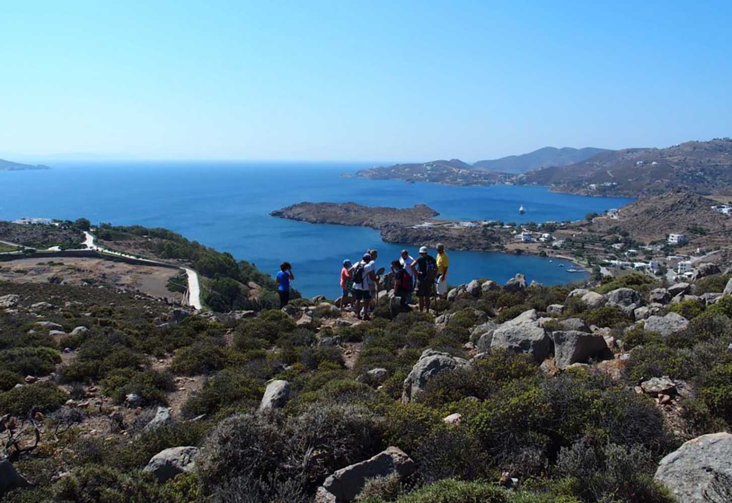 Ομάδα ανθρώπων σε πετρώδες τοπίο με θέα στη θάλασσα.